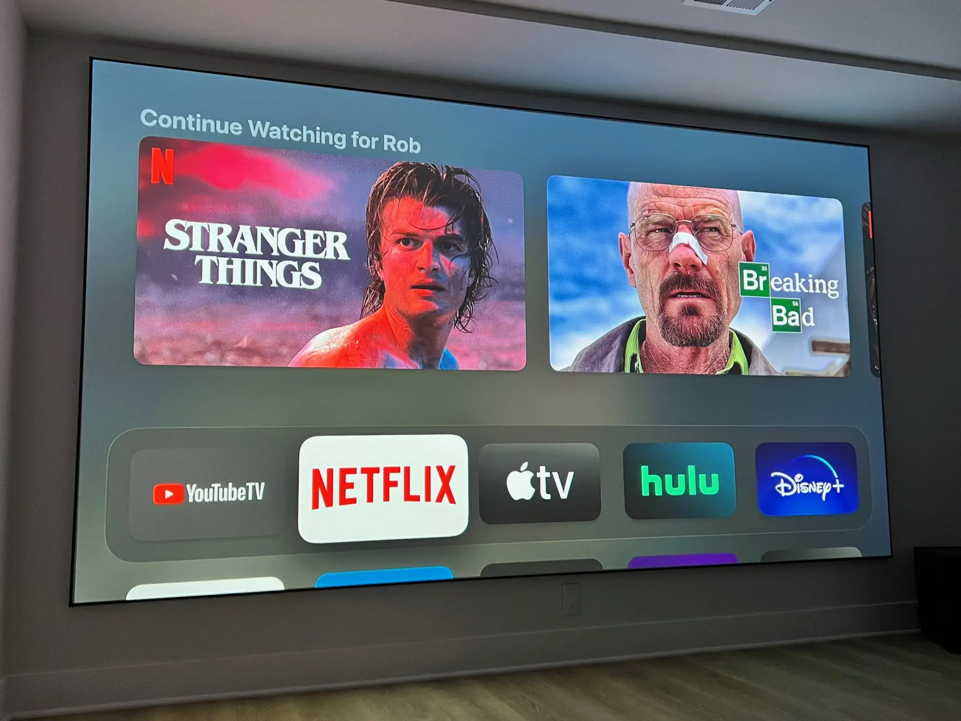 Smart home theater setup displaying popular streaming apps like Netflix and Hulu on a 150-inch projector screen.