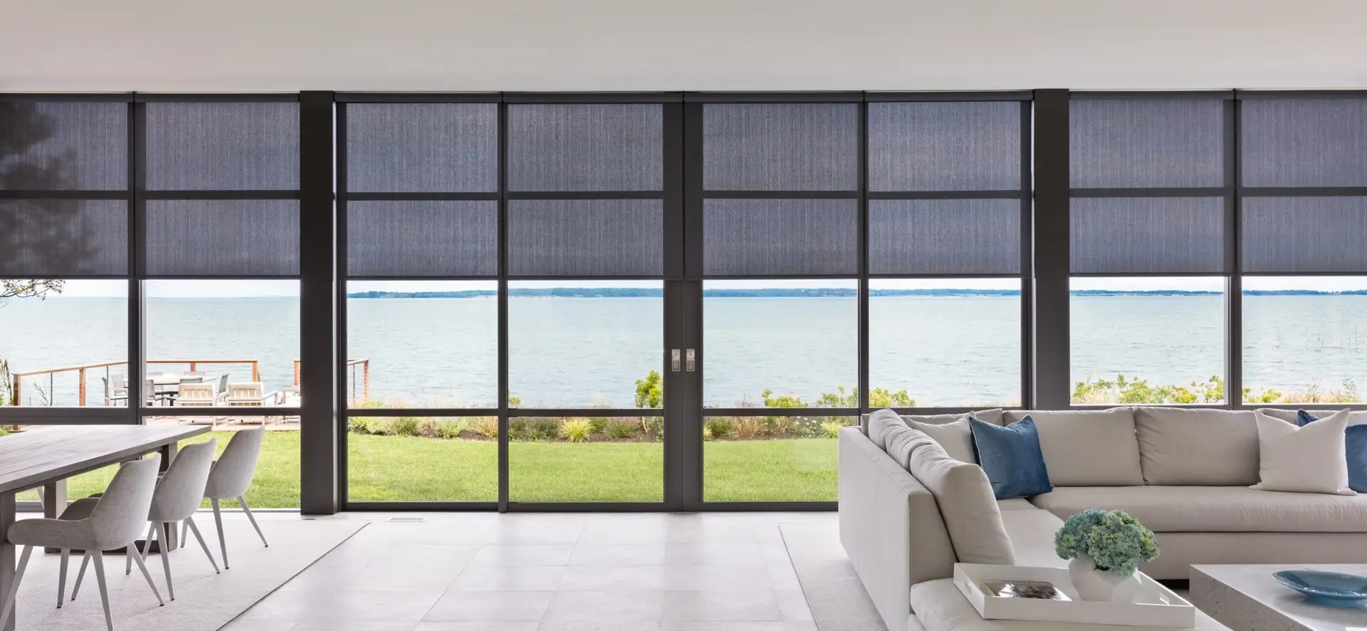 Living room with Savant motorized shades, offering sleek design and light control while showcasing a stunning lake view